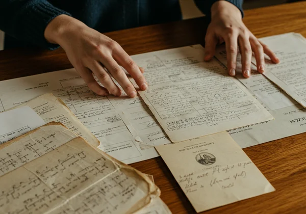 Hands sorting old documents, report cards, journals